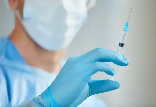 A medical professional in surgical attire holding a syringe, preparing for a non-surgical penis filler procedure to enhance girth safely and effectively