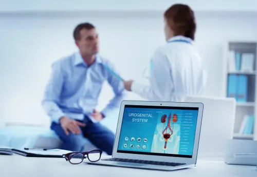 Male patient consulting with urologist about penile health concerns, with laptop showing urogenital system diagram during discussion of penile filler lumps and treatment.