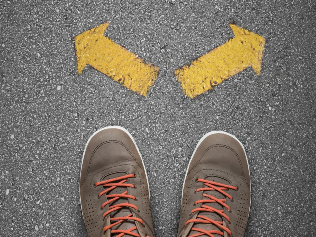 Decision concept for penis enlargement options—choosing between temporary and permanent paths (two arrows pointing left/right on pavement).